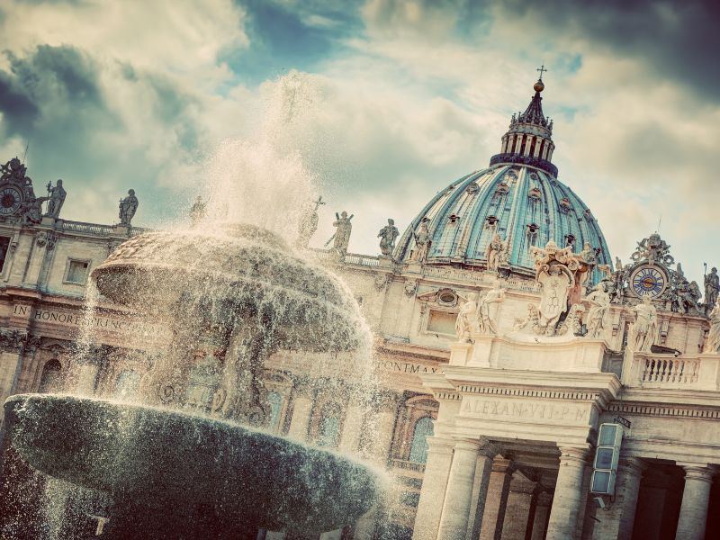 A photo portraying the vatican in the back and a fountain in the front. Represents the mysteries of the Vatican